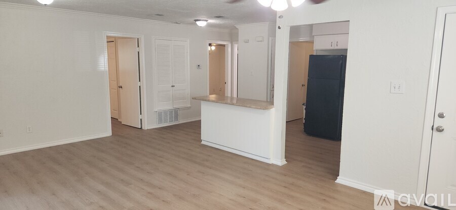 A spacious room with a white counter and a black refrigerator.