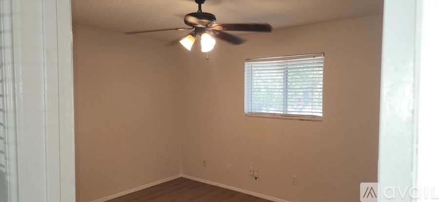 A room with a ceiling fan and a window with blinds.