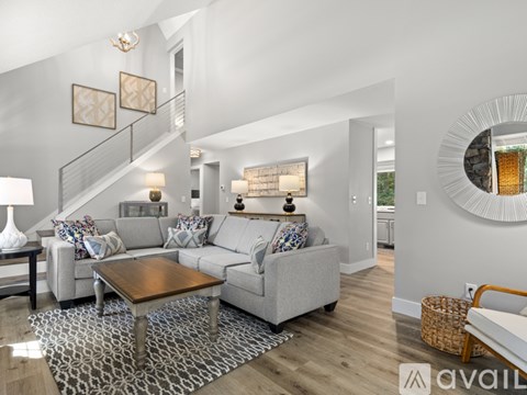 A living room with a grey couch, a coffee table, and a staircase.