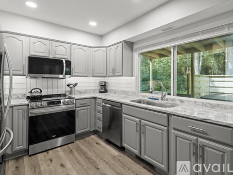 A modern kitchen with stainless steel appliances and wooden flooring.
