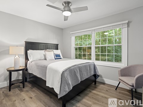A bedroom with a bed, chair, and window.