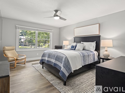 A bedroom with a bed, chair, and window.