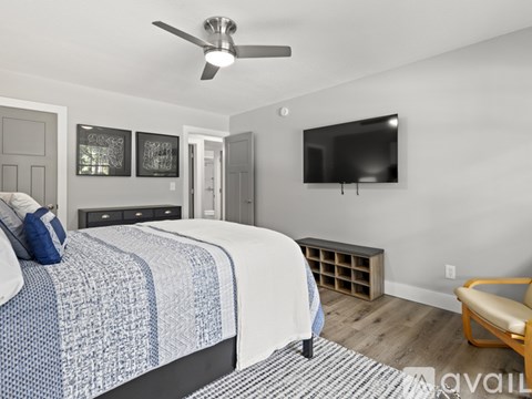 A bedroom with a bed, a chair, and a television.