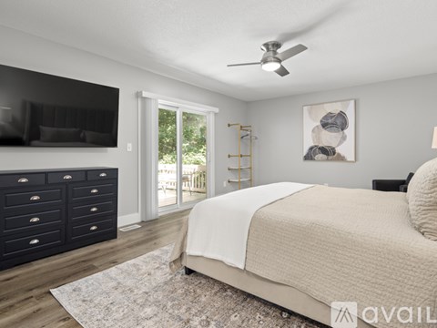 A bedroom with a large bed, a TV, and a sliding glass door.