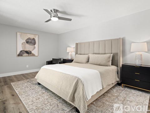 A bedroom with a large bed, a ceiling fan, and a painting on the wall.