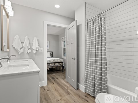 A bathroom with a white sink and a shower with a grey curtain.