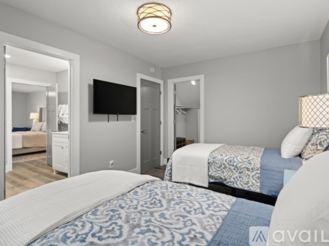 A bedroom with two beds and a television mounted on the wall.