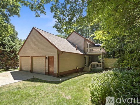 A house with a brown roof and a garage is surrounded by greenery.