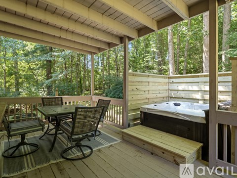 A wooden deck with a hot tub and chairs.