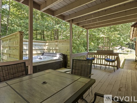 A wooden deck with a hot tub and chairs.