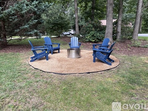 A set of blue chairs are arranged around a fire pit in a grassy area.