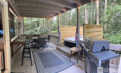 A patio with a grill and chairs overlooking a forest.