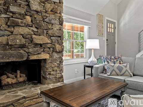 A stone fireplace with a wooden table in front of it.