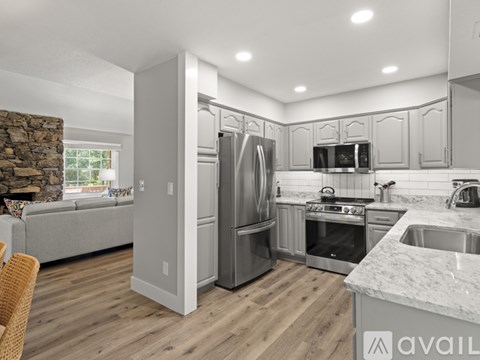 A modern kitchen with stainless steel appliances and wooden flooring.