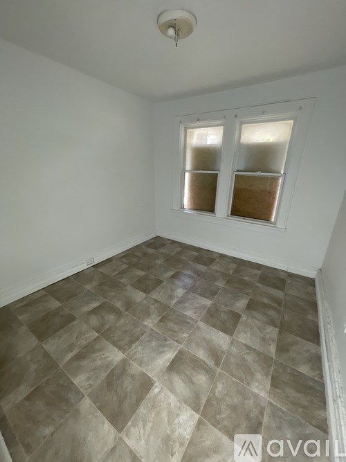 A room with a tiled floor and two windows.