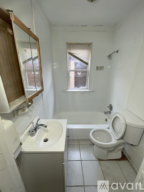 A bathroom with a toilet, sink, and mirror.