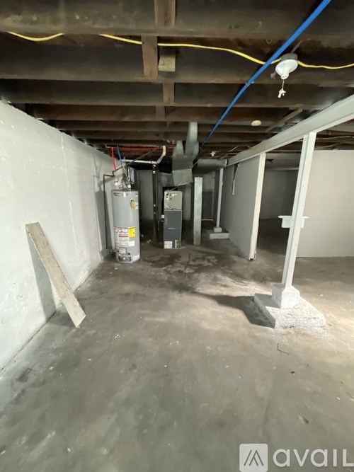 A room under construction with exposed pipes and a furnace.