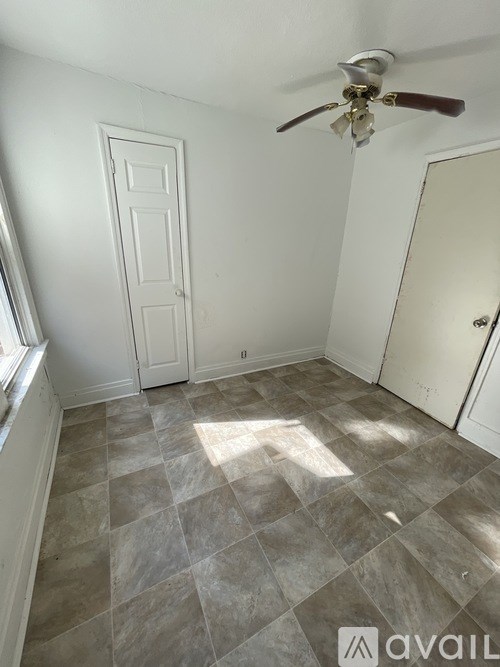 A room with a ceiling fan and tile flooring.