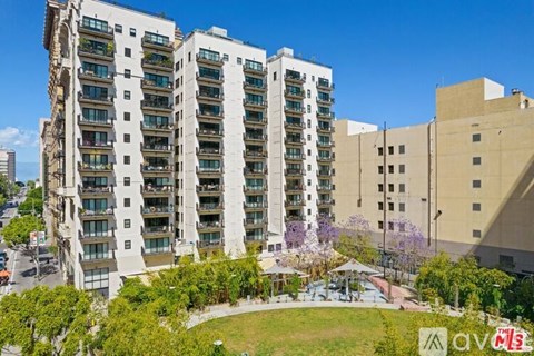 A tall apartment building with balconies and a green lawn in front.