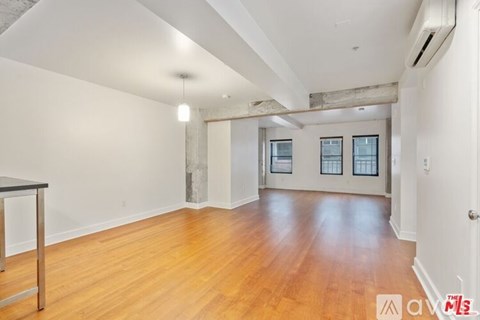 A spacious room with wooden floors and a large window.