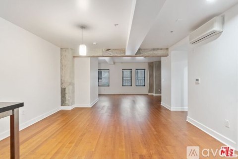 A spacious room with wooden floors and a large window.