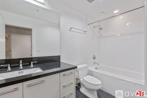 A white bathroom with a black counter top and a white toilet.