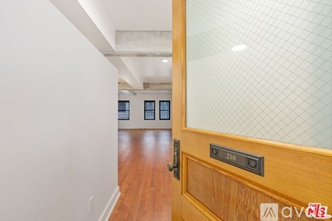 A wooden door with a glass panel and a black handle with the number 210 on it.