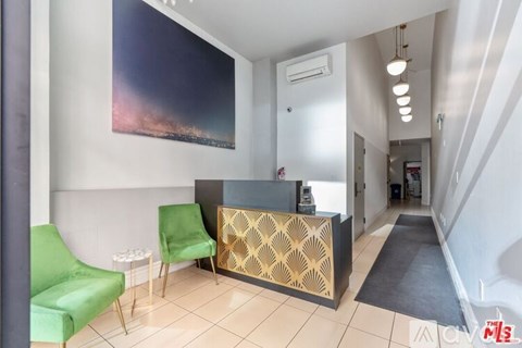 A reception area with a green chair and a painting on the wall.