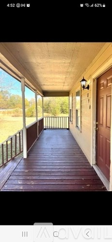 A wooden porch with a red door and a lantern hanging from the ceiling.