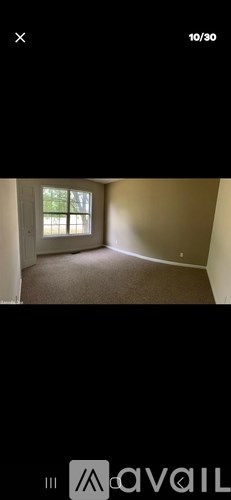 A room with a window and a carpeted floor.