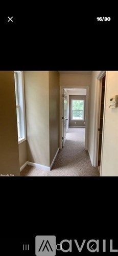 A hallway with beige walls and a carpeted floor.