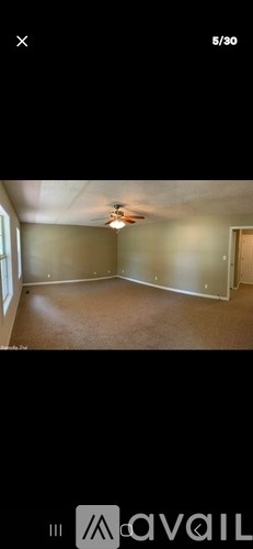 A room with a carpeted floor and a ceiling fan.