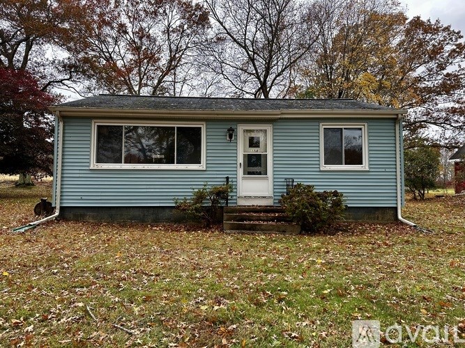 A small blue house with a white door and two windows.