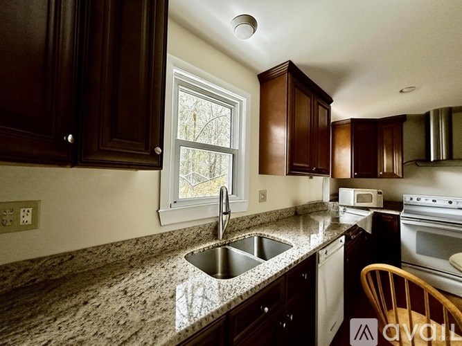 A kitchen with brown cabinets and a granite countertop.
