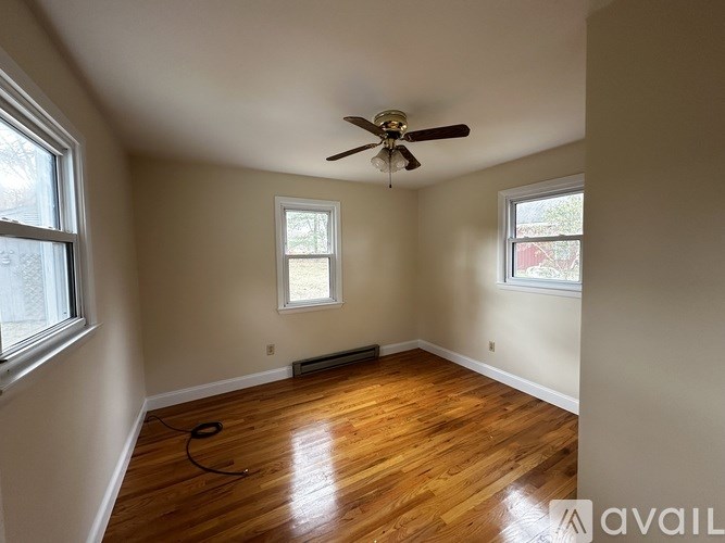 A room with a ceiling fan and wooden flooring.