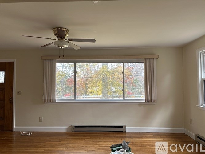 A room with a ceiling fan and a window with a view of trees.