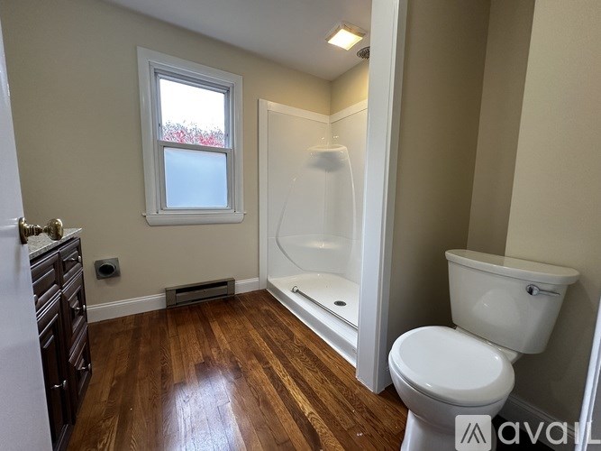 A house with a gray siding and a white door is surrounded by fallen leaves.