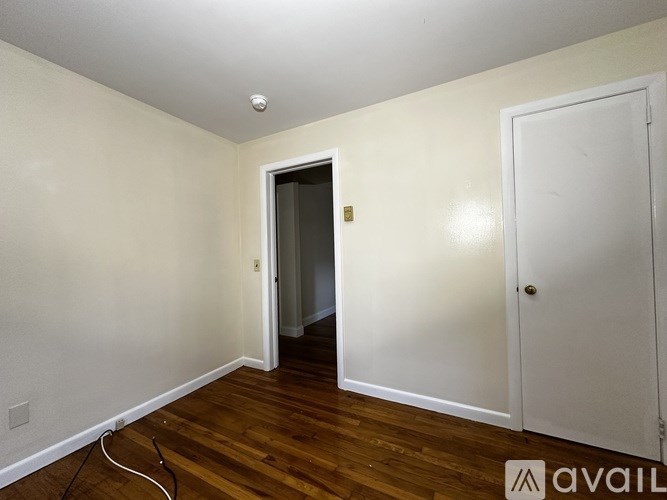A room with a white door and a white wall with a wooden floor.