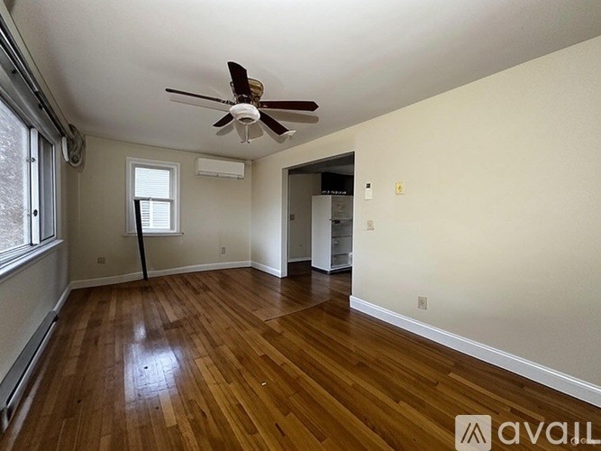 A room with a ceiling fan and wooden flooring.