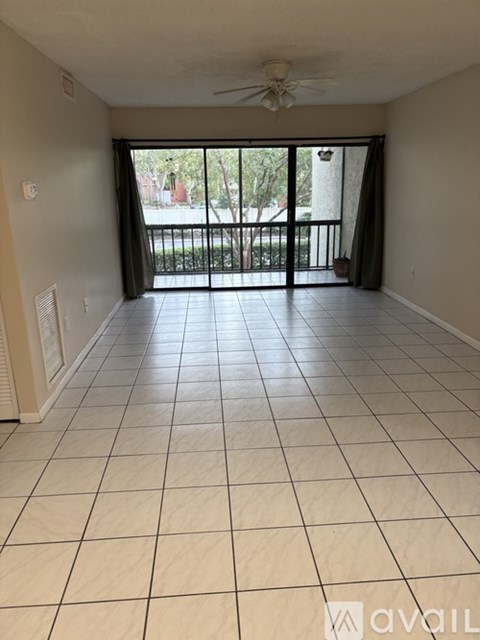 A spacious room with a sliding glass door leading to a balcony.