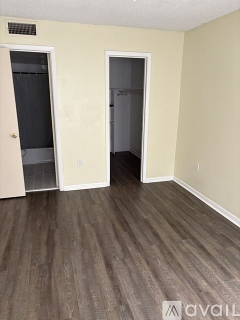 A room with a wooden floor and two open doors.