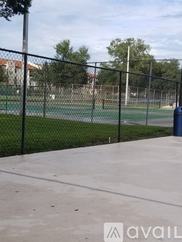 A tennis court is surrounded by a black fence.