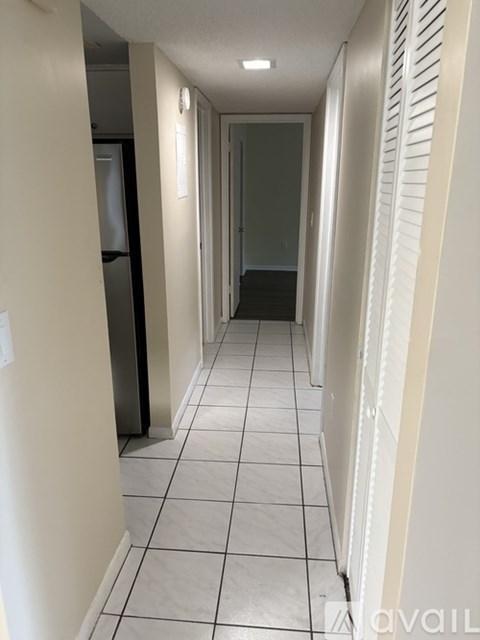 A long hallway with white tile floors and white walls.