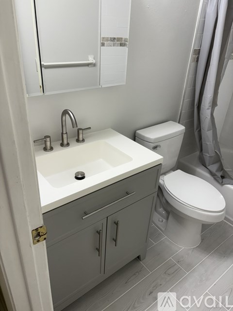 A white sink with a silver faucet and a white toilet in a bathroom.