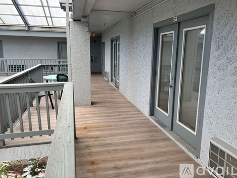 A balcony with a wooden floor and glass doors.