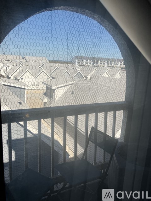 A balcony with a metal railing and a view of a parking lot.