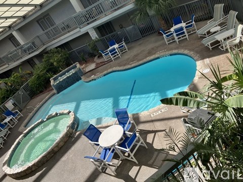 A pool with a hot tub and chairs around it.