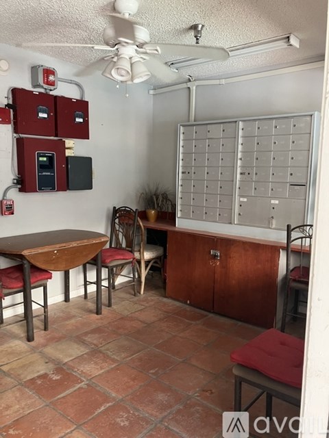 A room with a table, chairs and a fan.