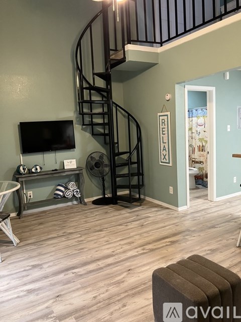 A living room with a spiral staircase and a flat screen TV.