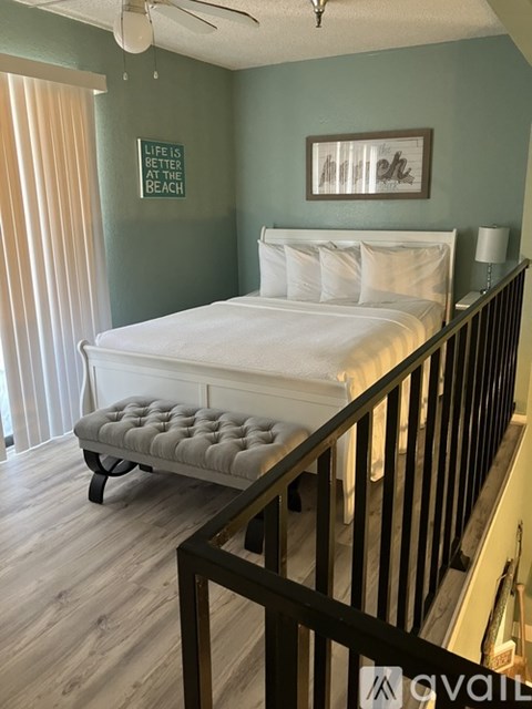A bedroom with a white bed and a black railing.